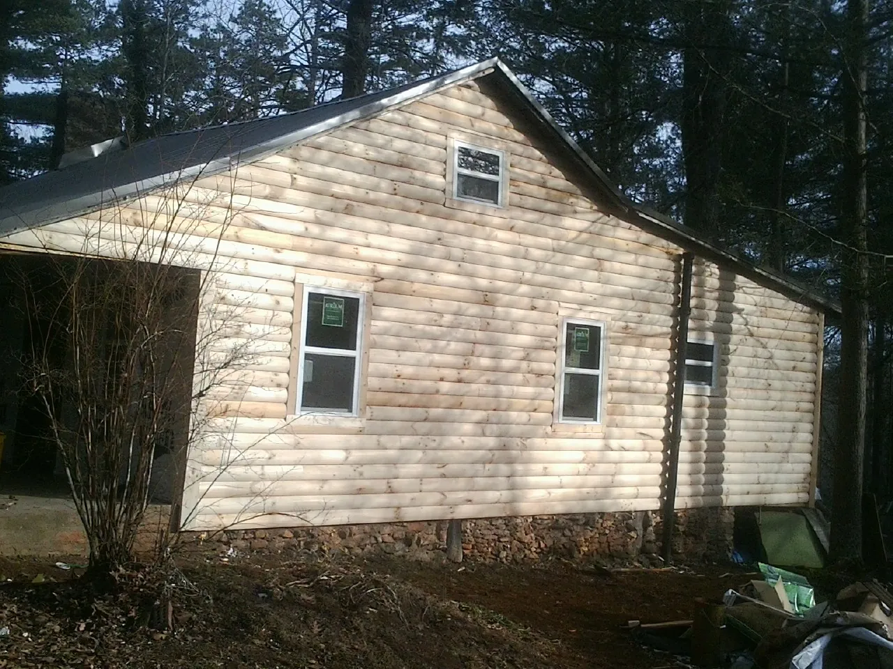 New log siding and dark metal roofing on a gable end in Cheltenham