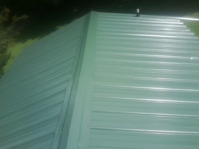 New green metal panels meeting at the ridge of a roof — Flat Roof Repair work by our crew in Cheltenham