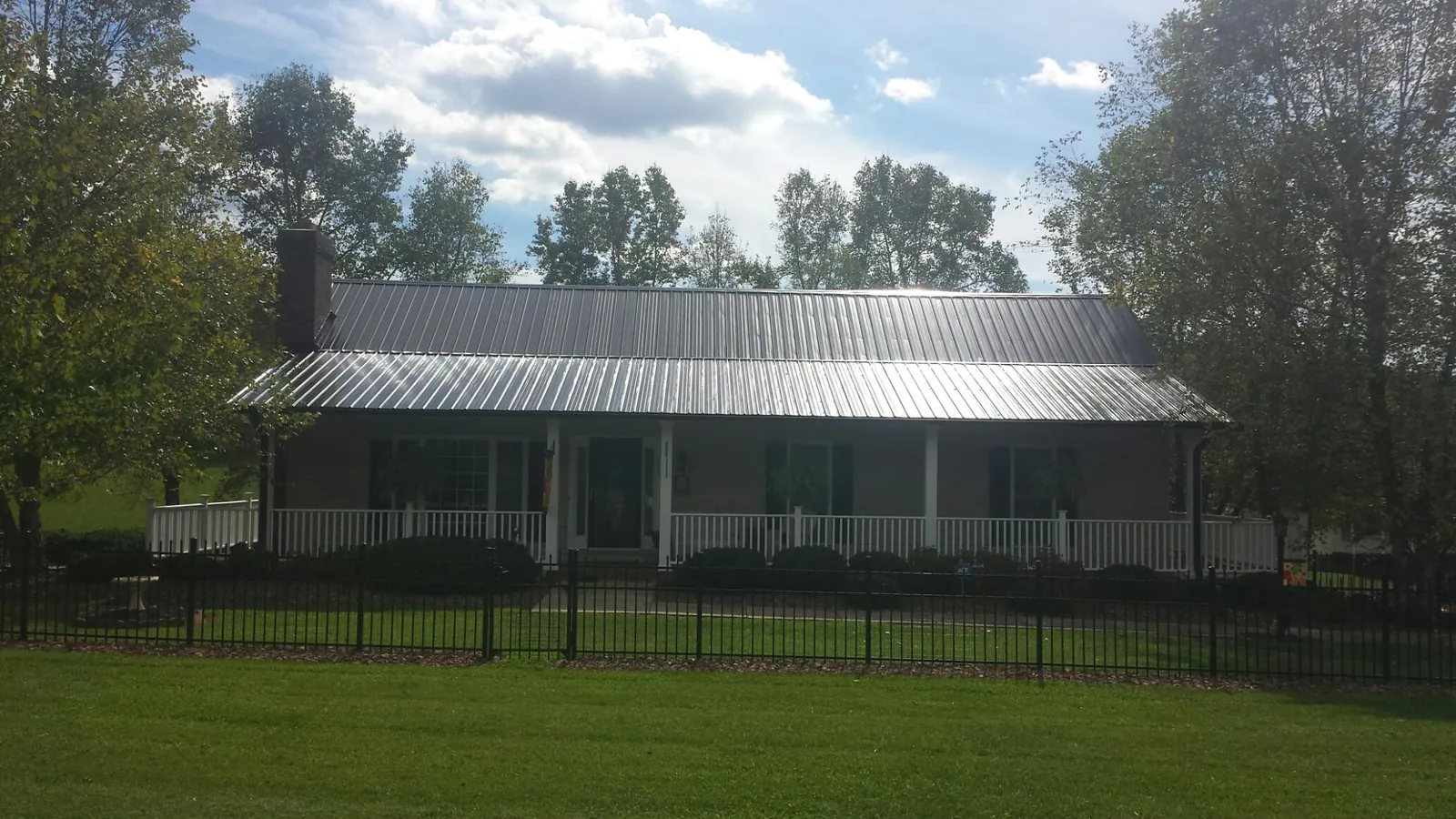 Gray metal roof on a brick ranch with a full width front porch — Gutter Guard Installation work by our crew in Cheltenham