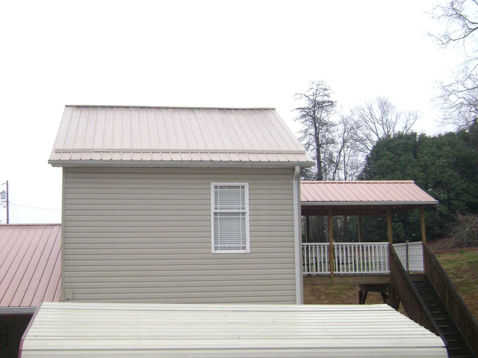 Tan metal roofs on a two story addition and attached porch, from a Roof Replacement job in Cheltenham